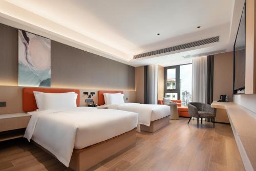 a hotel room with two beds and a desk at Wenchang Meilin Holiday Hotel in Wenchang