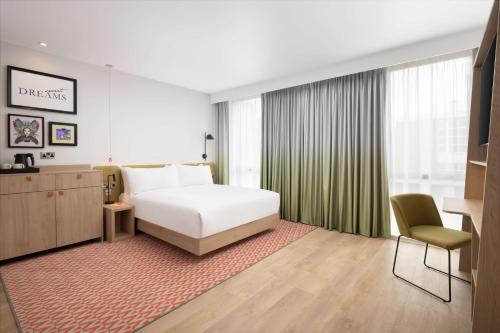 纽尼顿Hampton By Hilton Nuneaton的酒店客房,配有白色的床和椅子