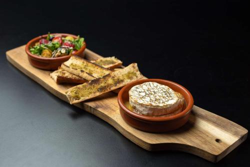 a wooden plate with two bowls of bread and a salad at DoubleTree by Hilton Paris Bougival in Bougival