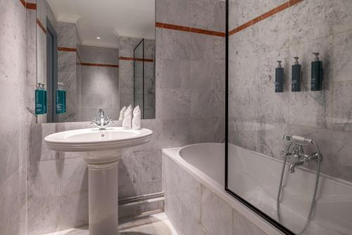 a bathroom with a sink and a shower and a tub at DoubleTree by Hilton Paris Bougival in Bougival
