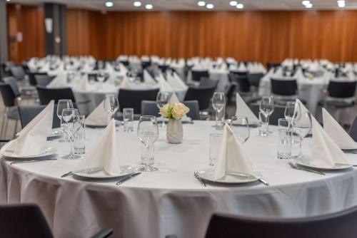 a room filled with tables with white tablecloths and glasses at DoubleTree by Hilton Paris Bougival in Bougival