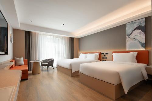 a hotel room with two beds and a couch at Wenchang Meilin Holiday Hotel in Wenchang