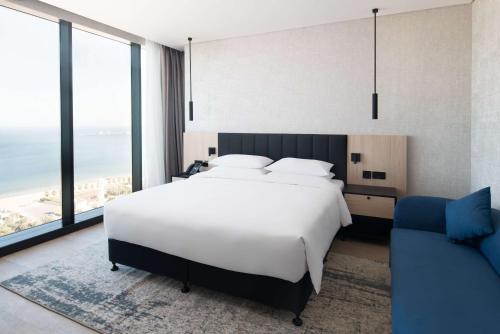 a bedroom with a large white bed and a blue chair at Park Inn by Radisson Hotel & Apartments Kuwait in Kuwait