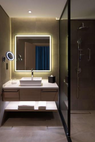 a bathroom with a sink and a mirror and a shower at Park Inn by Radisson Hotel & Apartments Kuwait in Kuwait