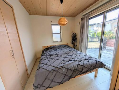 een slaapkamer met een bed en een groot raam bij メイプルヒルイン府中多磨 in Fuchu