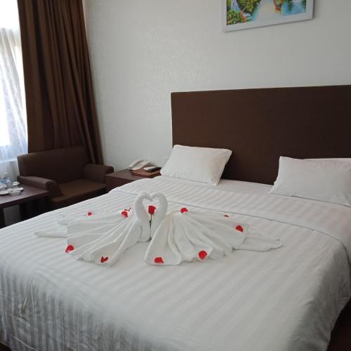 two swans dressed in white are on a bed at Bình Minh Hotel in Ha Tinh