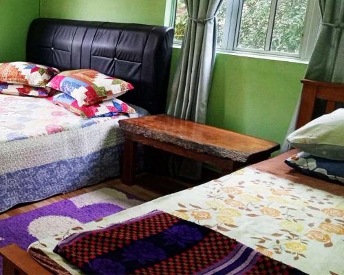 a bedroom with two beds and a table and a window at Homestay Langkawi Airport in Kampung Padang Masirat