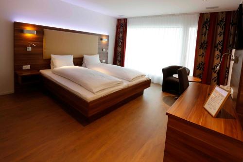 a bedroom with a bed and a desk and a window at Hotel Schützenhaus in Uznach