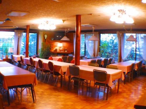 een eetkamer met tafels, stoelen en ramen bij Country Inn Kashiwabara in Hakuba
