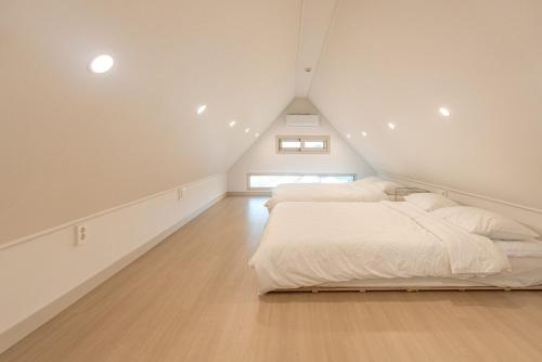 a attic bedroom with two beds and a window at Jeju Stayra in Jeju