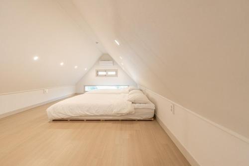 a white bedroom with a bed in the attic at Jeju Stayra in Jeju