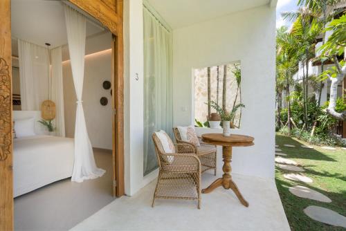 a porch with a table and chairs and a bed at The Balangan Hotel in Jimbaran