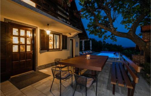 a wooden table and chairs on a patio at night at Beautiful Home In Bedenica With Sauna in Bedenica