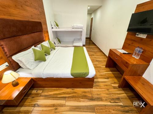 a bedroom with a bed with green and white pillows at Hotel Wraveler Inn Mussoorie in Mussoorie