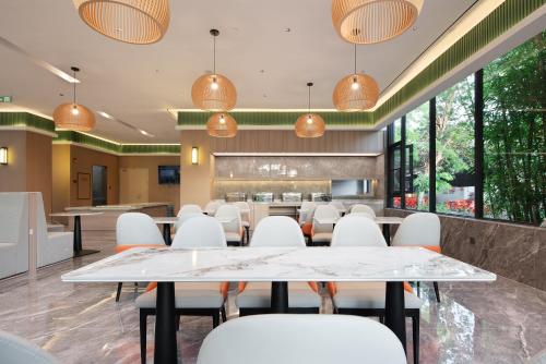 a conference room with white chairs and tables and windows at Wenchang Meilin Holiday Hotel in Wenchang