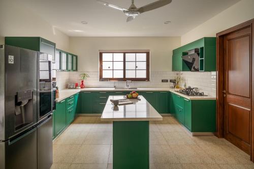 a green kitchen with green cabinets and a counter at Melhor stays Villas - UL- C2 7BHK villa with private pool, Assagao in Assagao
