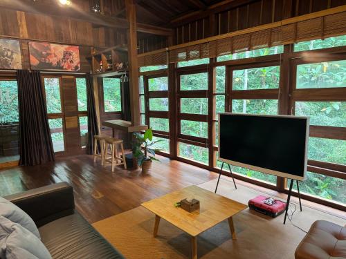 a living room with a large screen tv in a room with windows at Mii Paa Aii มิ๊ ป๊ะ ไอ in Chiang Mai