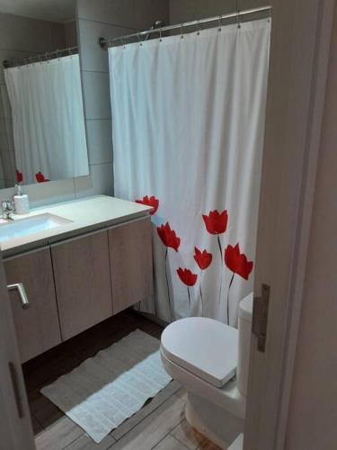 a bathroom with a toilet and a shower curtain with red flowers at Depto Ñuñoa 5 pers 2 baños estacionamiento cerca estadio in Santiago