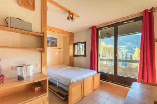 une chambre avec un lit et une grande fenêtre dans l'établissement Génépi - Studio pour 5 vue montagne, à Vars