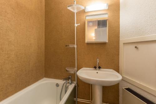 une salle de bain avec un lavabo et une baignoire dans l'établissement Faliju - appartement avec vue montagne, à Vars