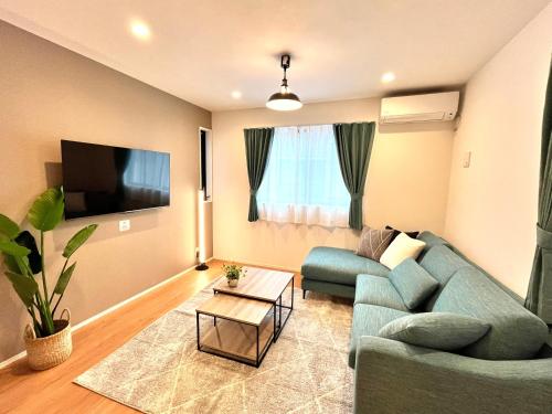 a living room with a blue couch and a tv at Casa Stella 4 by Liaison in Osaka