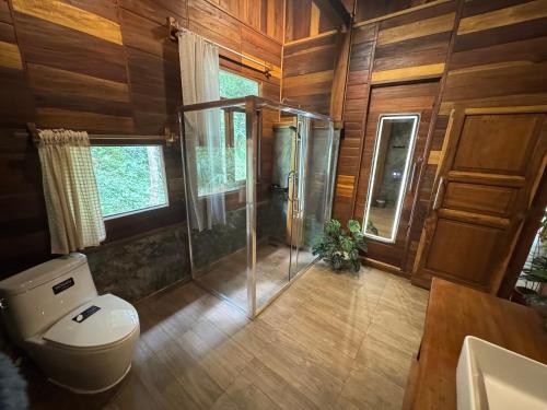a bathroom with a toilet and a glass shower at Mii Paa Aii มิ๊ ป๊ะ ไอ in Chiang Mai
