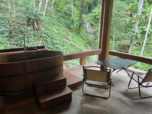 a bathroom with a tub and a table and chairs at Mii Paa Aii มิ๊ ป๊ะ ไอ in Chiang Mai