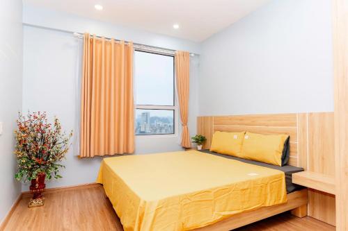 a bedroom with a yellow bed and a window at Mon La Maison Sapphire Ha Long - Amazing View in Ha Long