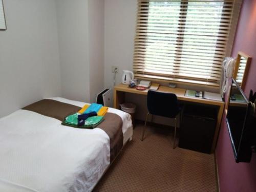 a hotel room with a bed and a desk and a window at Ashiwada Hotel in Fujikawaguchiko