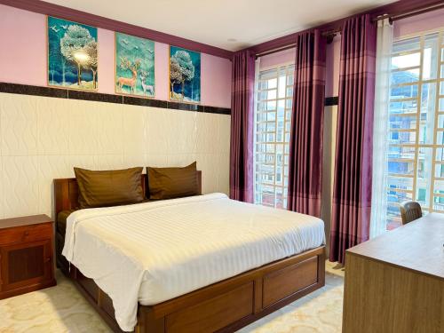 a bedroom with a bed with purple walls and windows at The Cozy Corner-Budget Hotel in Phumĭ Kâmpóng Kândal