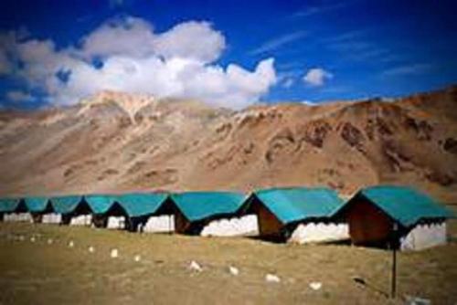 a building with blue roofs in front of a mountain at Mulkila Adventure Camp in Leh