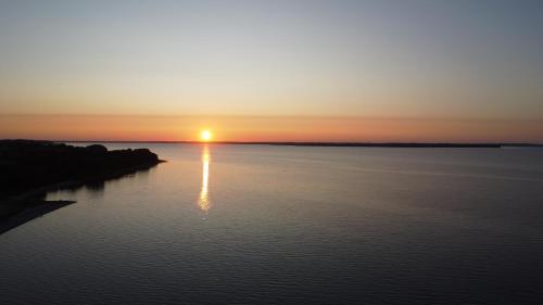 a sunset over a body of water with the sun setting at Landhaus Habernis in Steinberg