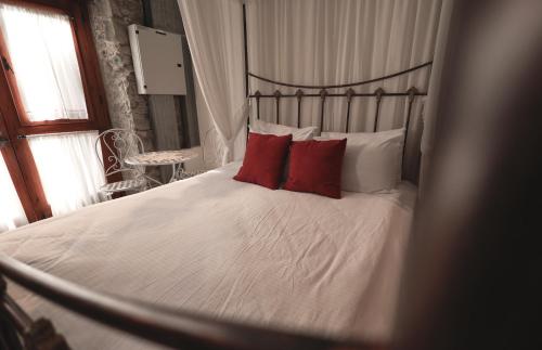 a bedroom with a bed with red pillows at Vasilikis House in Kalopanayiotis