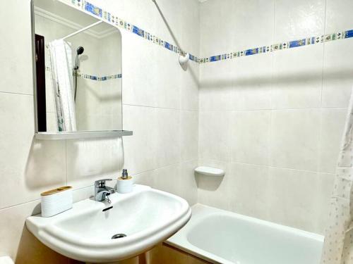 a white bathroom with a sink and a tub at El piso de Carmen in Portosin