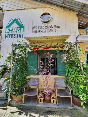 a building with two chairs and a window with plants at Chậm Homestay Đà Lạt in Da Lat