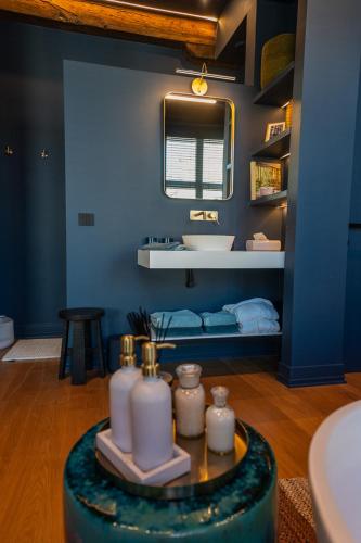 a blue bathroom with a sink and a table with candles at Maison Brunon in Bruges
