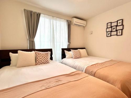 two beds in a room with a window at Casa Stella 7 by Liaison in Osaka