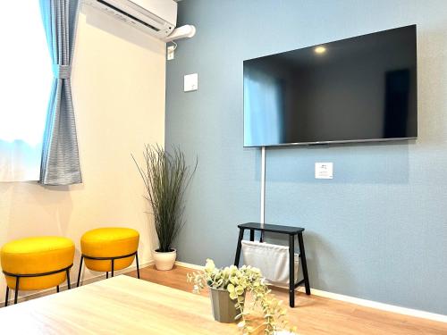 a dining room with two chairs and a television on a wall at Casa Stella 7 by Liaison in Osaka