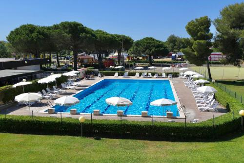 a swimming pool with white umbrellas and chairs at IssTravel, Holiday Homes with common swimming-pool in Marina di Bibbona from 400 to 900 meters from the sea in Marina di Bibbona