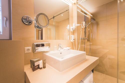 a bathroom with a sink and a shower and a mirror at Hotel Enzian - Adults Only in Obertauern