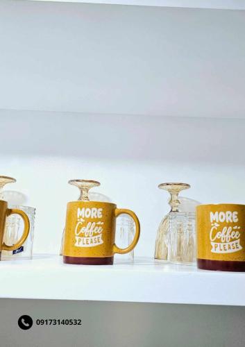 three coffee mugs on a shelf with glass jars at Gab's Place Sudio Unit, Marina Spatial in Dumaguete