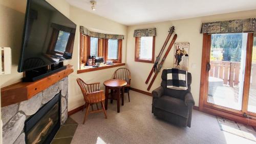 a living room with a television and a chair and a table at Timberline Village #46 home in Sun Peaks