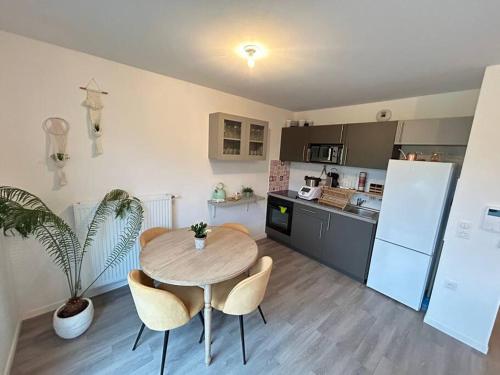 Una cocina con una mesa y sillas en una cocina. en Appartement récent tout confort, en Caen