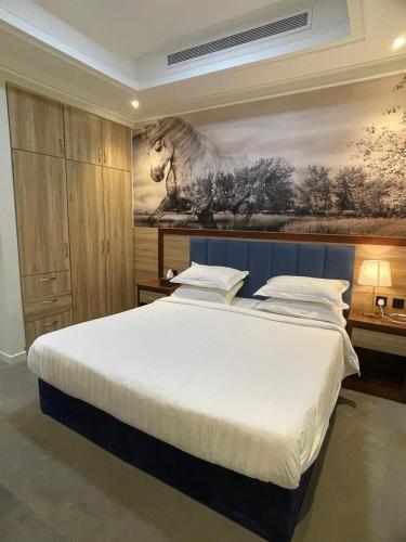 a bedroom with a large bed with a painting on the wall at عز الدولية للشقق المخدومه Ezz International for Serviced Apartments in Jeddah