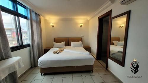 a hotel room with two beds and a mirror at Residence Blue Sky in Douala