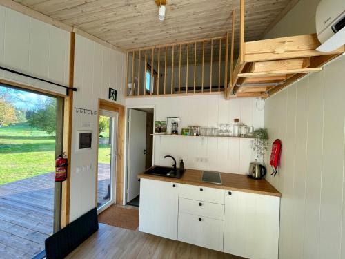 a kitchen with white cabinets and a wooden ceiling at Paluküla tiny house Kadaka in Paluküla