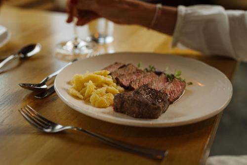 a plate of steak and potatoes on a table at Berghotel Engstligenalp Adelboden in Adelboden