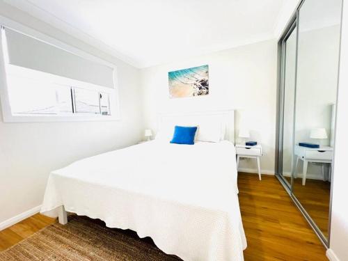 a white bedroom with a large white bed with a blue pillow at Private & Cozy villa for you! in Sutherland