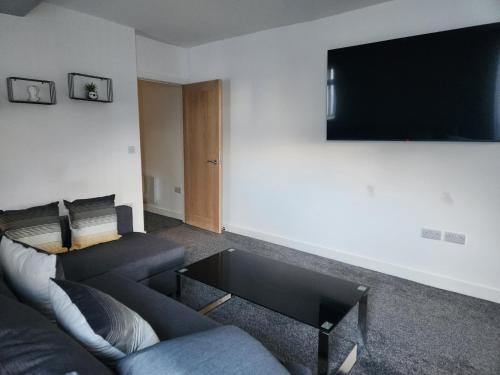 a living room with a couch and a flat screen tv at Centre Apartment - Sleeps 2 & Roof Top Hot Tub in Derby