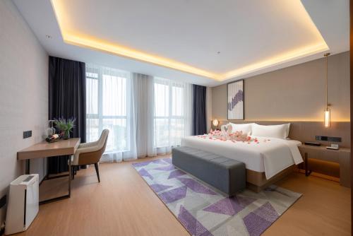 a hotel room with a large bed and a desk at Lavender Hotel Xinle Shijiazhuang Airport Hebei Academy of Fine Arts in Xinle